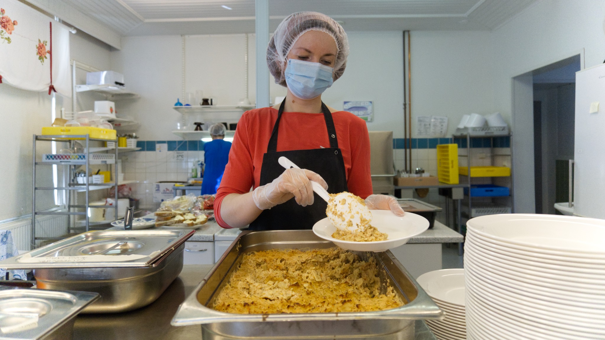 Kouluemäntä panee ruokaa lautaselle, kuva